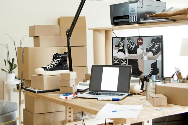 a laptop on a table with boxes and shoes, suggesting digital transformation needed